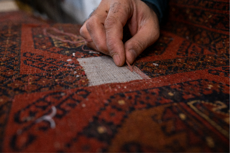 Close-up of expert craftsman hand-repairing oriental rug with traditional techniques