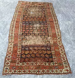 Before restoration: heavily worn vintage oriental rug showing significant damage and fading